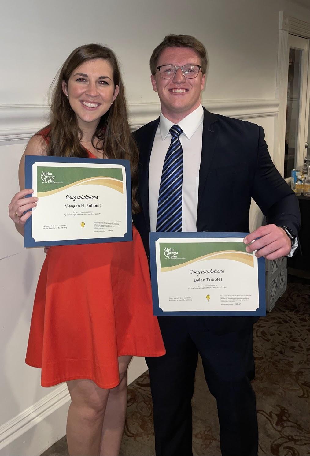 Meagan Robbins and Dylan Tribolet holding up their nomination certificates from the Alpha Omega Alpha Honor Medical Society.